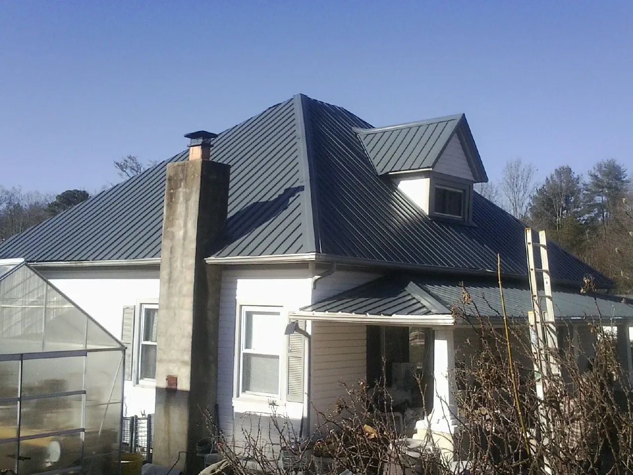 Dark blue standing seam metal roof on a white farmhouse with dormer — Slate & Tile Roof Repair by Roofing Brothers in Fairless Hills