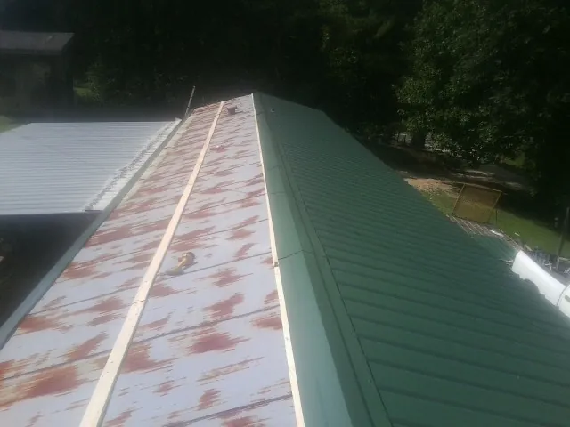 Old rusted panels beside newly installed green metal roofing — Wind Damage Roof Repair by Roofing Brothers in Fairless Hills