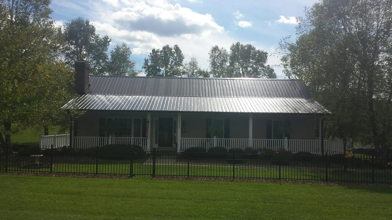 Gray metal roof on a brick ranch with a full width front porch — Gutter Guard Installation work by our crew in Fairless Hills
