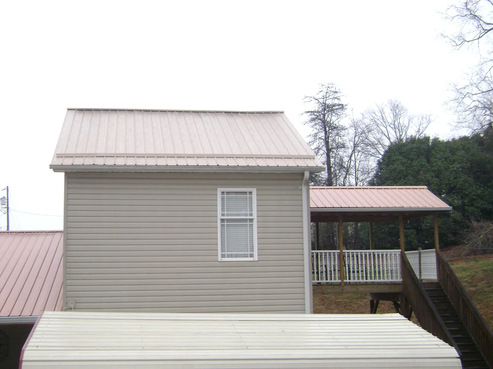 Tan metal roofs on a two story addition and attached porch, from a Roof Replacement job in Fairless Hills