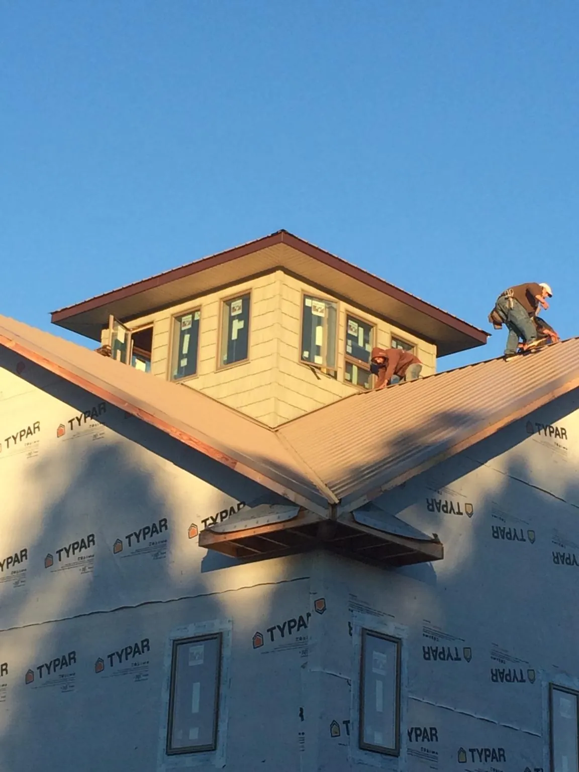 Roofers working around a rooftop cupola on a new metal roof at sunset — Roof Waterproofing in Fairless Hills by Roofing Brothers